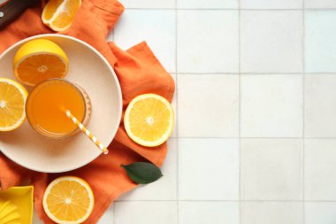 Bir bardak taze portakal suyu ve beyaz fayanslı kesilmiş meyve tabağı.