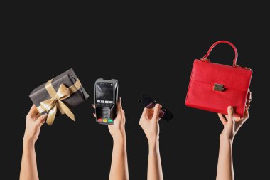 Ödeme terminali olan kadın eller, hediye kutusu ve karanlık arka planda aksesuarlar. Kara Cuma indirimi