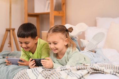 Cep telefonlu şirin çocuklar evlerinde video oyunları oynuyorlar.