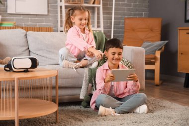 Evde video oyunu oynayan tabletli şirin, mutlu çocuklar.