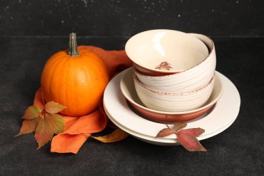 Masada sonbahar dekorlu ve balkabaklı tabak yığını var.