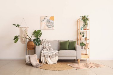 Rahat kanepe, raf ünitesi ve odada Monstera bitkisi.