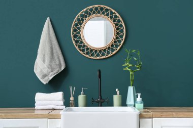 Lavabo ve banyo aksesuarları banyodaki yeşil duvarın yanında.