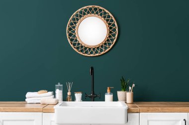 Lavabo ve banyo aksesuarları banyodaki yeşil duvarın yanında.