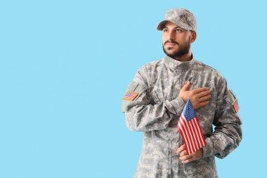 Amerikan bayrağı taşıyan erkek asker mavi arka planda dua ediyor. Gaziler Günü kutlamaları