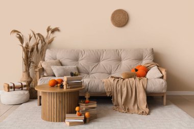 Konforlu kanepe, sehpa ve sonbahar dekoru oturma odasındaydı.