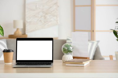 Boş bir dizüstü bilgisayar, kahve fincanı ve oturma odasındaki programcının masasına bitki.