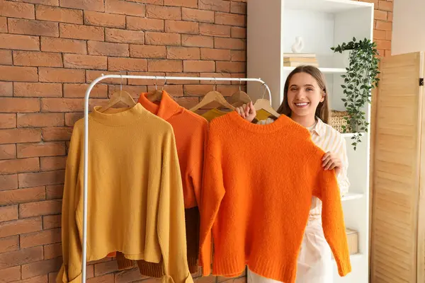 Güz kıyafetlerini soyunma odasından alan güzel genç bir kadın.