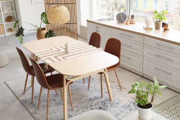 Mutfağın içinde yemek masası, tezgah ve bitkiler var.