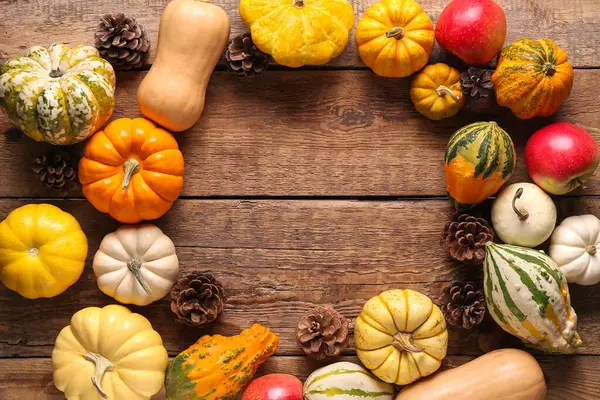 Ahşap zemin üzerinde taze balkabağı, elma ve çam kozalaklarından yapılmış çerçeve