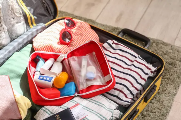 Açık ilk yardım çantası, yerde şık kıyafetler.