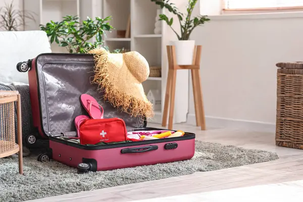 İçinde ilk yardım çantası, şık kıyafetler ve hasır şapka olan bavullar.