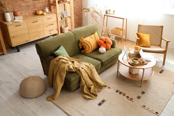 İçinde yeşil kanepe, koltuk ve balkabağı olan oturma odası.