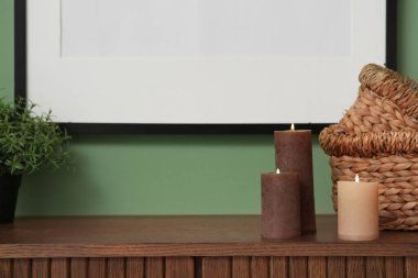 Ahşap dolapta yanan mumlar ve hasır sepetler.