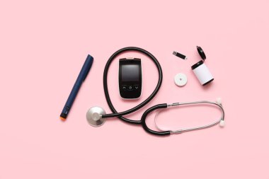 Kalemli glukometre, glukoz sensörü ve pembe arka planda steteskop. Diyabet kavramı