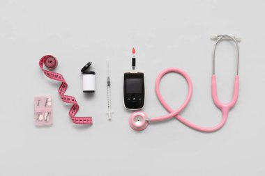 İnsülin, steteskop ve ışık arka planında mezura bulunan bir glukometre. Diyabet kavramı