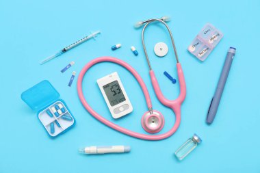 Kalemli glukometre, steteskop ve mavi arka planda haplar. Diyabet kavramı