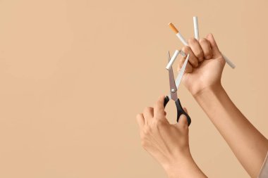 Bej arka planda sigara kesen kadın. Sigara içmeyi bırak