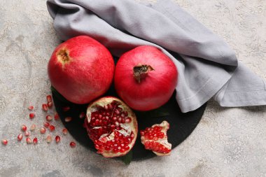 Taze olgun narı ve gri arka planda tohumları olan siyah tahta.