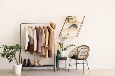 Oturma odasındaki koltuğun yanında farklı şık kıyafetler ve botlarla dizilin.