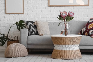 Oturma odasındaki masada protea çiçekleri olan vazo.