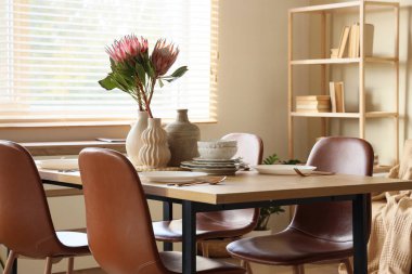 Yemek odasında vazolar ve protea çiçekleri olan masa.