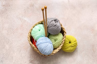 Renkli örgü ipliği ve hafif grunge arka planında iğneler olan hasır sepet.