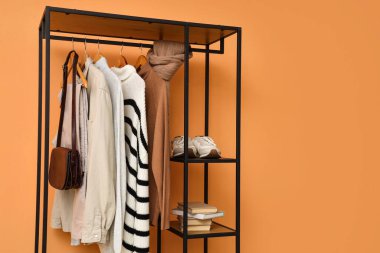 Turuncu arka planda şık kıyafetler, ayakkabılar ve aksesuarlar.