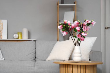 Oturma odasındaki masasında manolya çiçekli vazo.