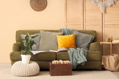 Koltuk, kahve masası, ev bitkisi ve kitap tutacağı.