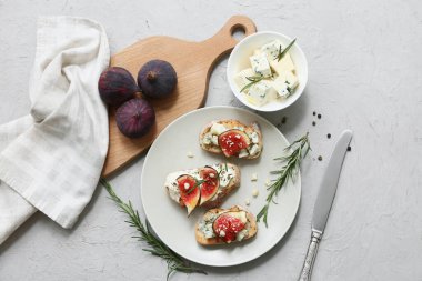 Beyaz zemin üzerinde ricotta ve mavi peynirli lezzetli incirli bruschetta tabağı.