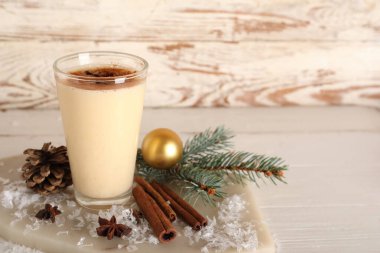 Yıldız anason, tarçın, köknar dalı ve beyaz ahşap arka planda noel balosuyla nefis bir eggnog kokteyli.