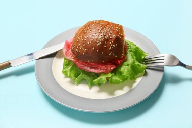 Lezzetli hamburger tabağı ve mavi arka planda plastik. Mikro Plastik Farkındalık Ayı