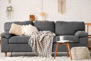 Oturma odasındaki sehpanın üzerinde açık bir kitap ve çay.