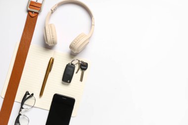 Modern kulaklıklı ve beyaz arka planda cep telefonlu şık erkek aksesuarları.