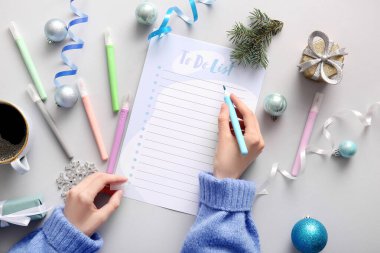 Işık arka planında Noel dekoru olan kadın yapılacaklar listesi yazıyor