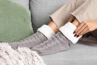 Sıcak çoraplı bir kadın evdeki kanepede oturuyor.