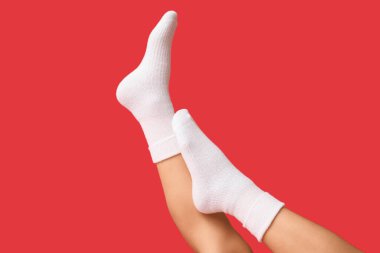 Kırmızı arka planda beyaz pamuklu çoraplı genç kadın bacakları