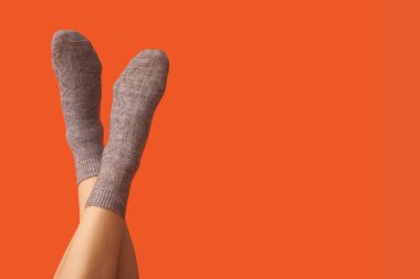 Turuncu arka planda gri pamuklu çoraplı genç kadın bacakları