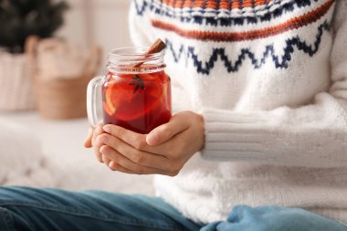 Kadın elinde sıcak şarap kavanozu tutuyor, yakın plan.
