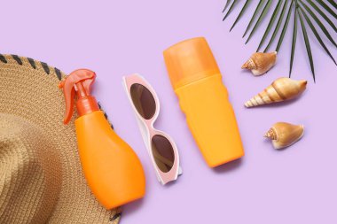 Güneş kremi, güneş gözlüğü, şapka ve arka planda palmiye yaprağı olan kompozisyon