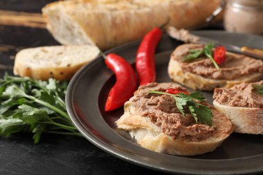 Kızarmış ekmek tabağı, lezzetli börek, acı biber ve siyah ahşap arka planda maydanoz.