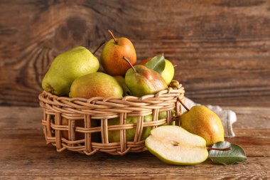 Ahşap zemin üzerinde tatlı olgun armutlar olan hasır kase.