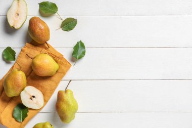 Tatlı olgun armutlar ve beyaz ahşap arka planda yapraklar