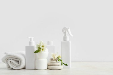 Farklı kozmetik ürünleri seti, temiz havlu, spa taşları ve açık arkaplanda çiçekler
