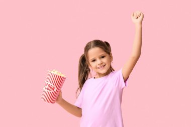 Pembe arka planda patlamış mısırı olan mutlu küçük kız