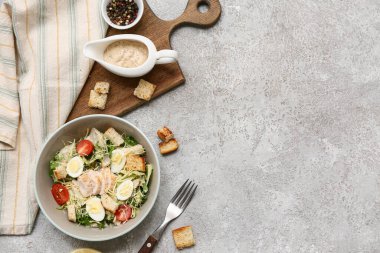 Lezzetli tavuklu Sezar salatası, biberli mısır ve gri arka planda sos teknesi.