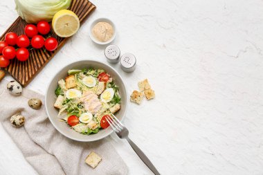 Lezzetli tavuklu Sezar salatası ve beyaz arka planda malzemeler.