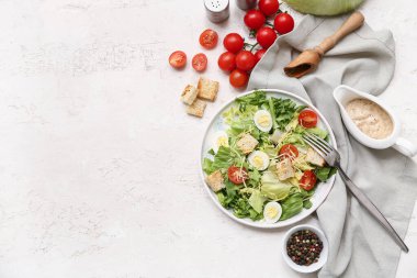 Lezzetli Sezar salatası ve beyaz arka planda malzemelerle dolu bir tabak.