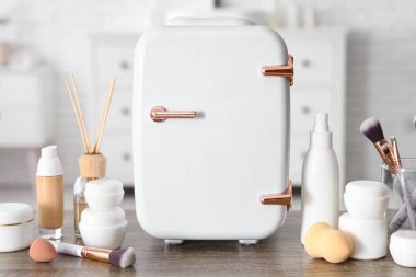 Beyaz arka planda krem ve temelleri olan küçük kozmetik buzdolabı. Yakın çekim.